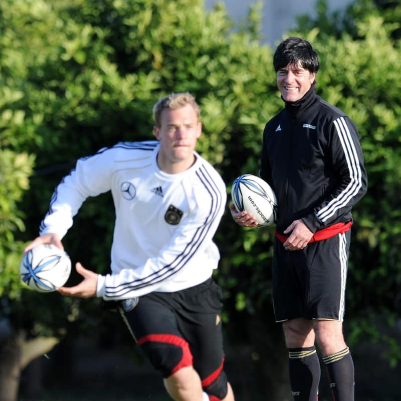 Goalkeeper Manuel Neuer (L) of Germany exercises with a rugby ball whilst German head coach Joachim Loew watches