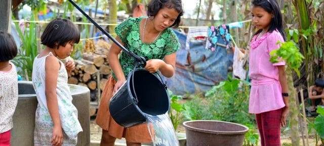 Young girls in a displaced persons camp in Myanmar collect water from a well.