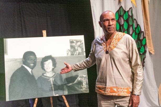 Phil Okwedy performing at his show The Gods Are All Here with a copy of the only photo he has of his parents
