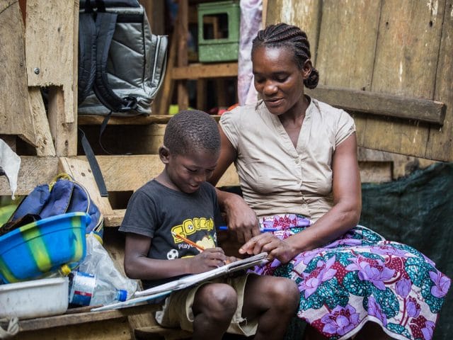 A mother helps her son with his homework at home in São Tomé and Príncipe.