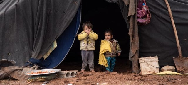 Displaced children stand in front of their family's tent in an informal camp in southern Syria. Displaced children stand in front of their family's tent in an informal camp in southern Syria.