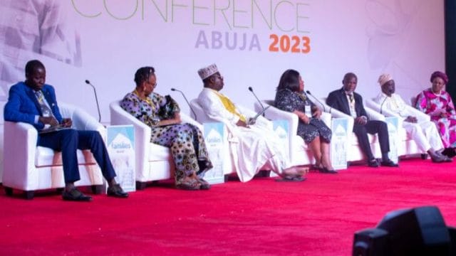 A panel of law, religion and education experts — Four men and three women — sit in white chairs with microphones discuss issues of marriage in Africa law