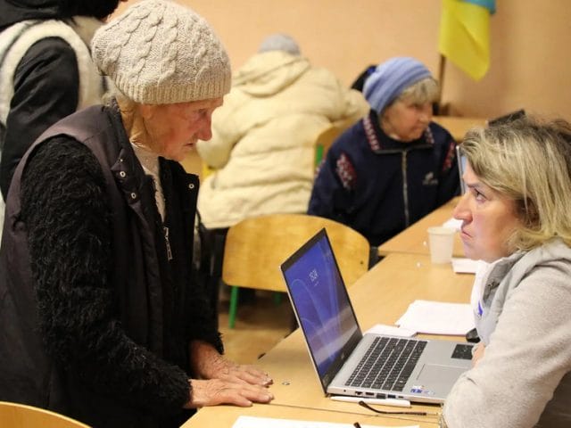 An aid worker registers an evacuated woman for multi-purpose cash assistance at the transit centre. An aid worker registers an evacuated woman for multi-purpose cash assistance at the transit centre.